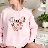 a woman sitting on a bed wearing a pink mickey mouse sweatshirt