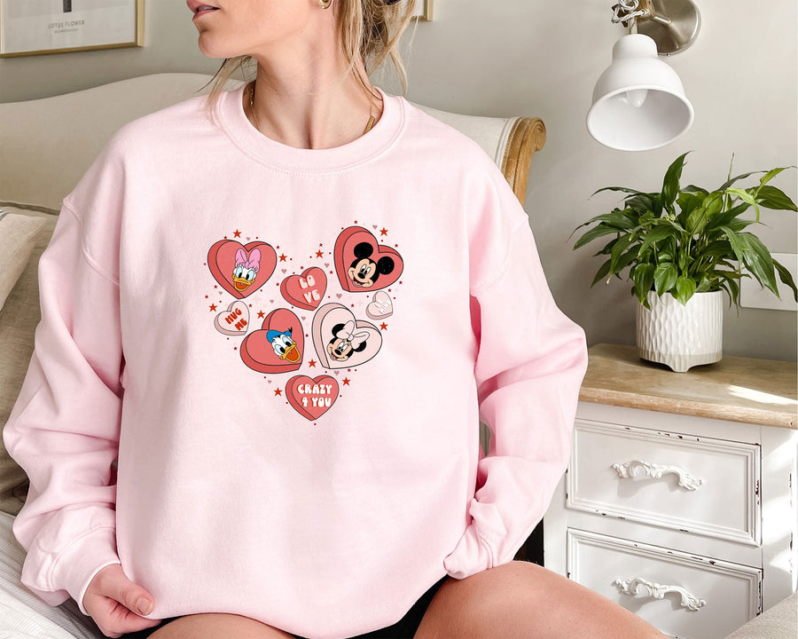 a woman sitting on a bed wearing a pink mickey mouse sweatshirt