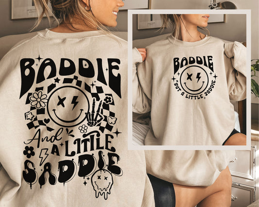 a woman wearing a sweatshirt that says baddie and a little saddie