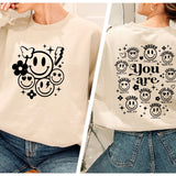 a woman wearing a sweatshirt with a smiley face on it