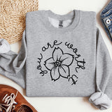 a sweatshirt with a flower on it next to a pair of shoes