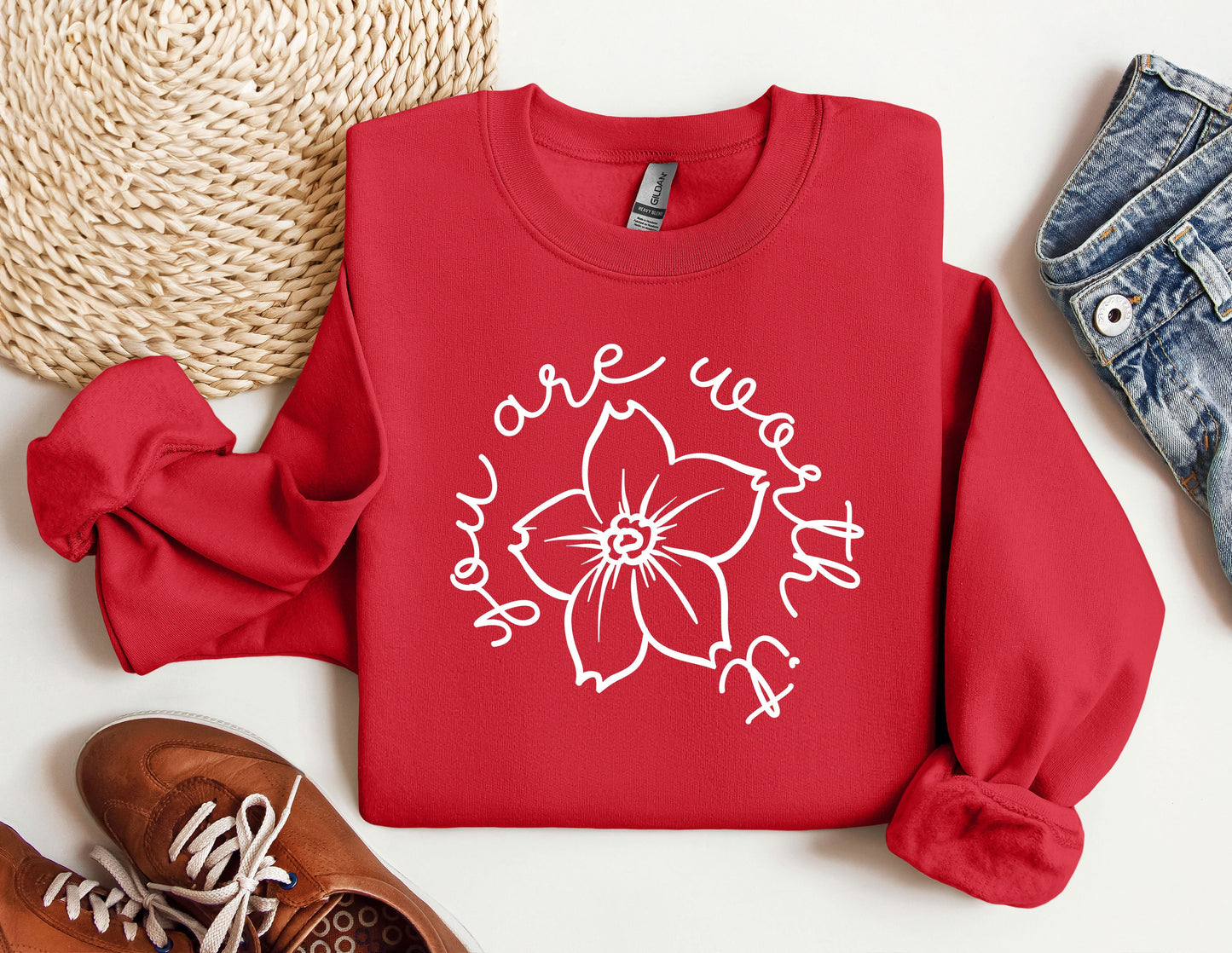 a red shirt with a flower on it next to a pair of shoes